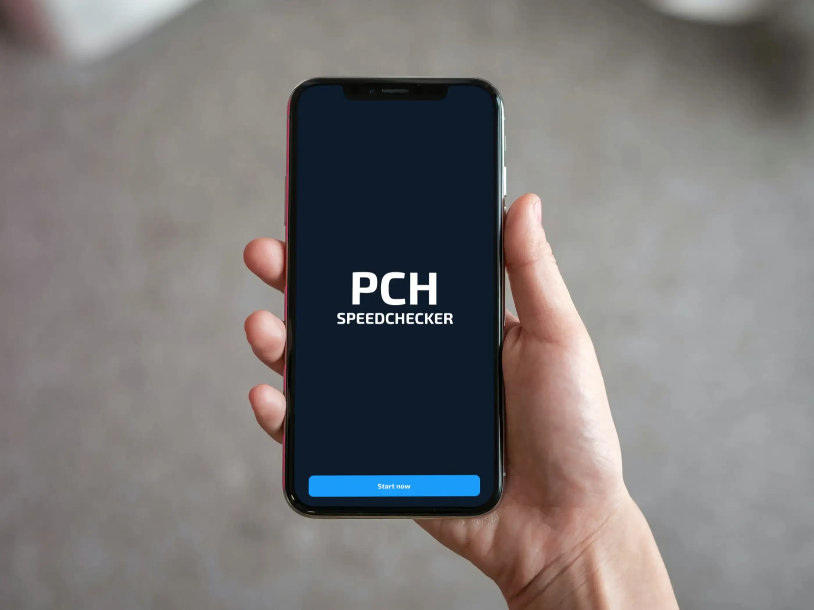 Hand holding a smartphone displaying the PCH Speedchecker app splash screen with its logo.